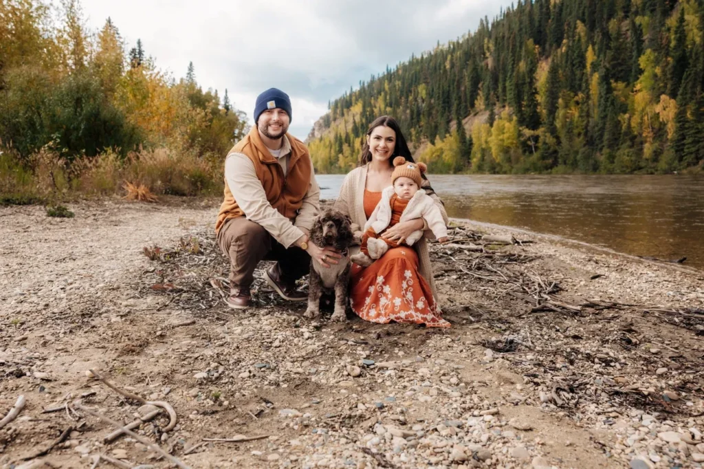 Andrew and Vivian with their baby son and cocker spaniel on the Salcha River shore in fall.