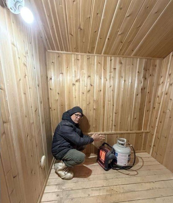 A builder crouched in the newly cedar-lined sauna next to a portable heater.
