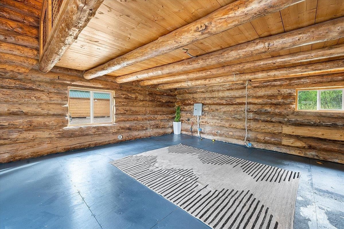 Renovated cabin interior with log walls, exposed log beams and a painted blue floor.