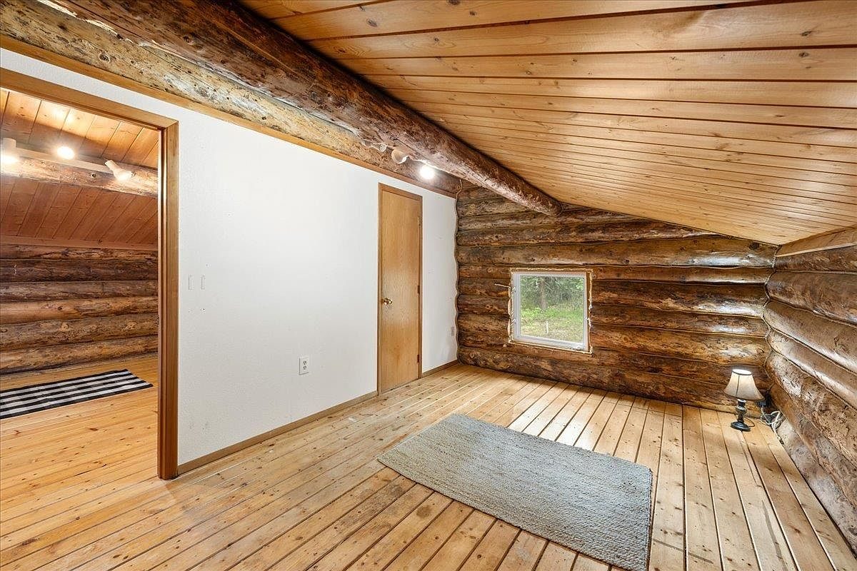 Upstairs room with log walls, a wood ceiling and new wood flooring.